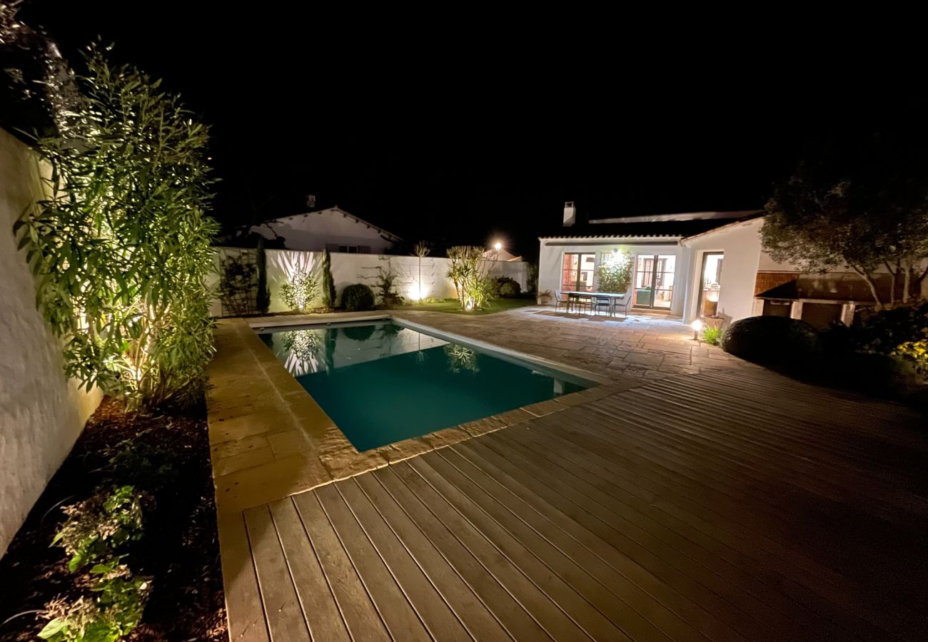 Terrace and swimming pool at night, surrounded by a lighted garden 