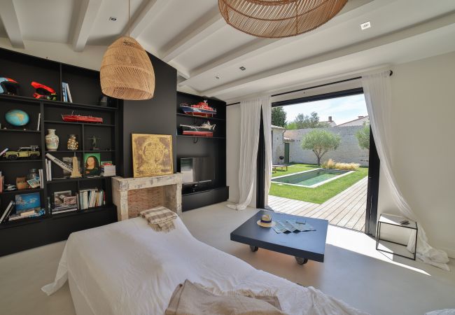 Living room with sofa and large shelves and bay window with garden and pool view