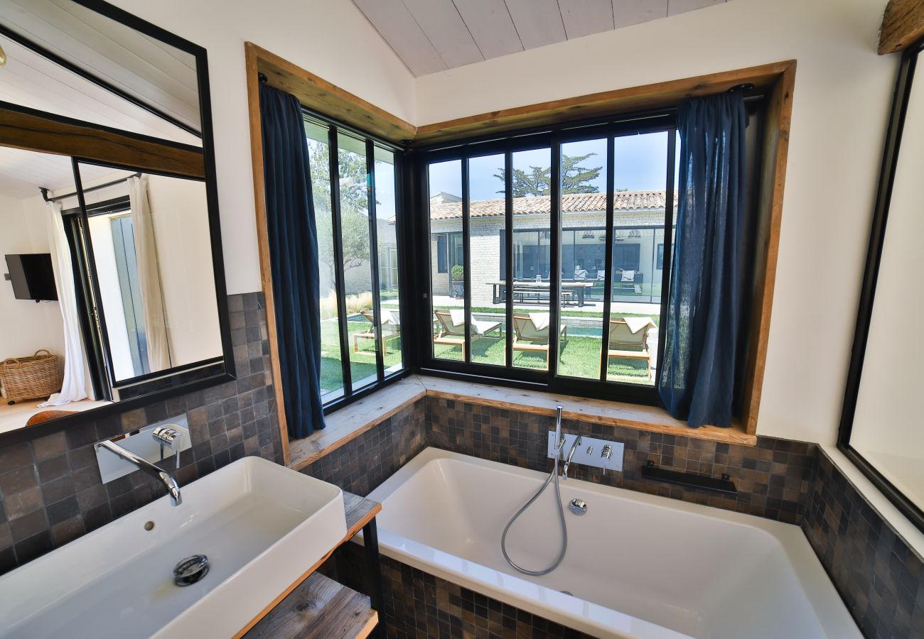 Salle de bain avec baignoire, vasque et vue sur le jardin 