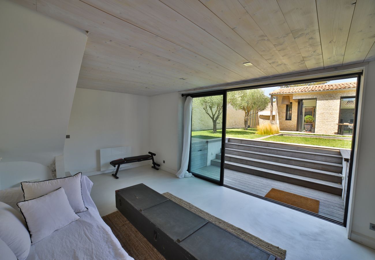 Grand salon avec canapé blanc et baie vitrée accès jardin 