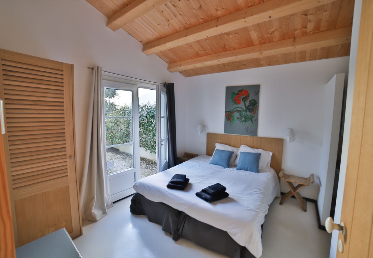 La chambre à coucher avec lit double et baie vitrée sur la jardin 