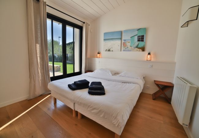 Chambre parentale avec lit kingsize, parquet et baie vitrée vue jardin