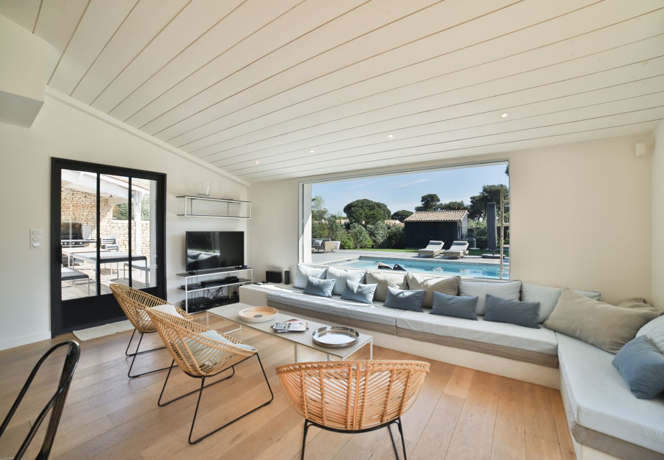 Salon avec grands canapés et ouverture sur la terrasse et piscine 