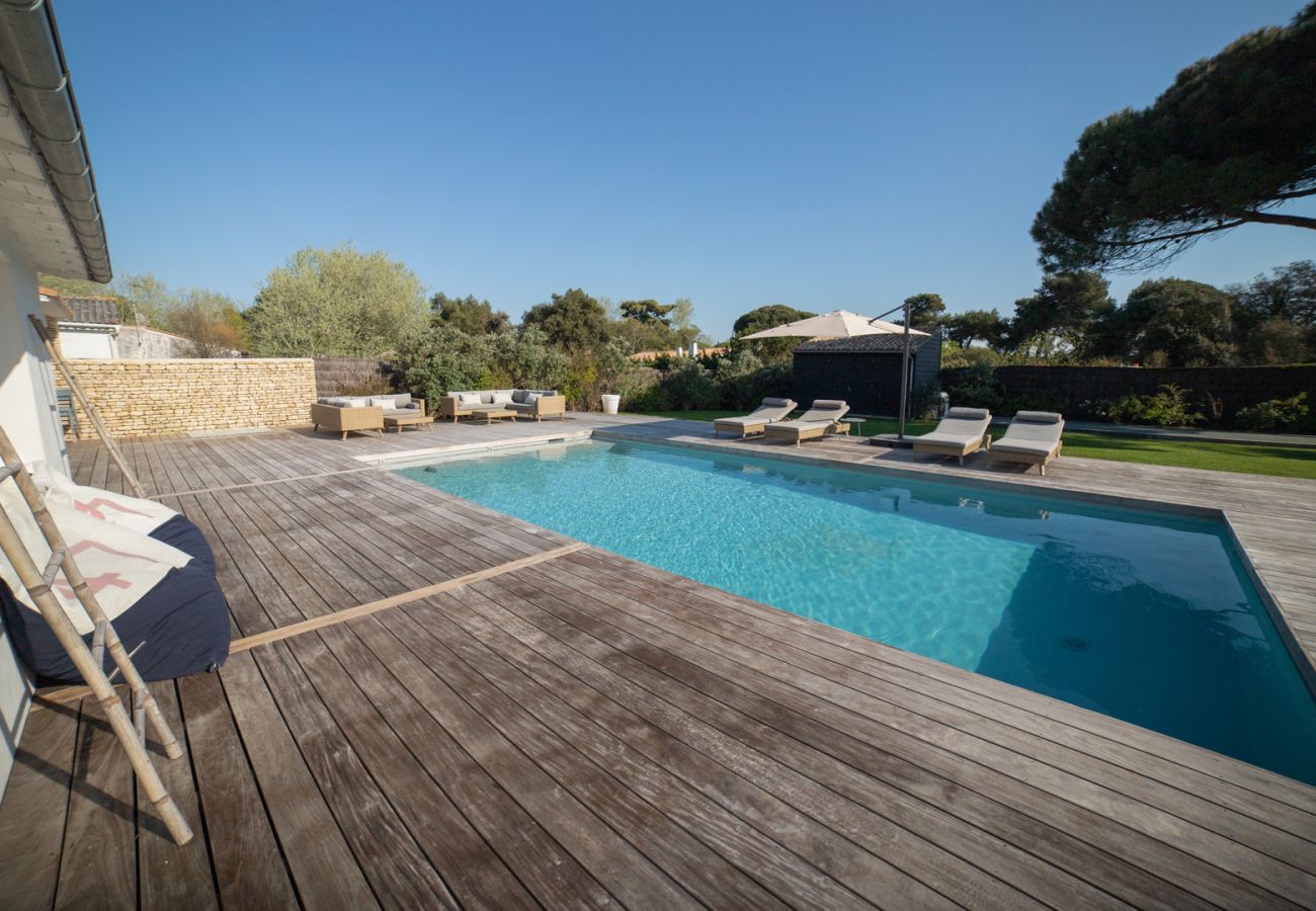 Vue terrasse en bois, piscine et chaises longues 