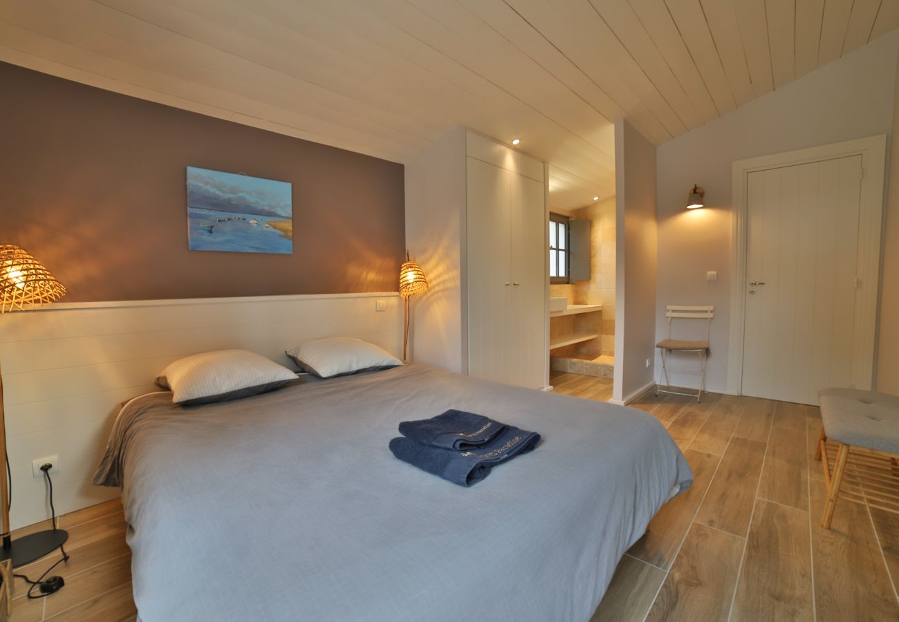 Chambre à coucher avec lit double, grande baie vitrée et accès au jardin 