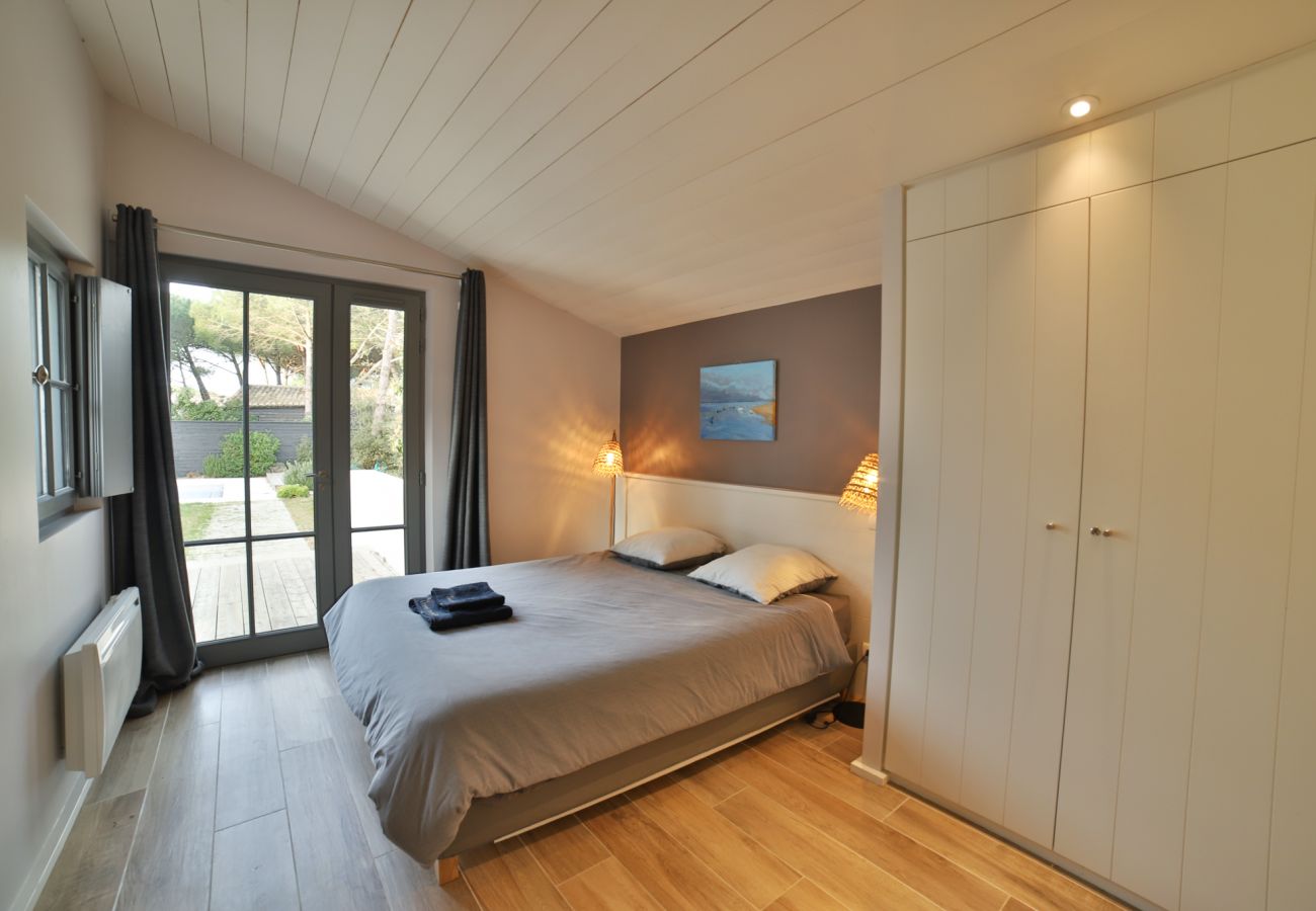Chambre à coucher avec lit double, grande baie vitrée et accès au jardin 